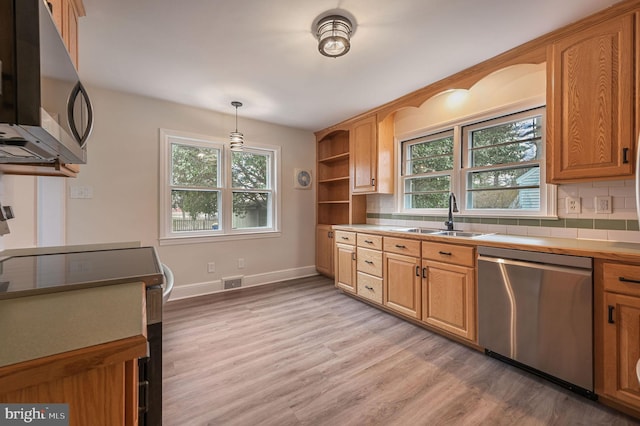 kitchen with light wood finished floors, stainless steel appliances, visible vents, decorative backsplash, and a sink