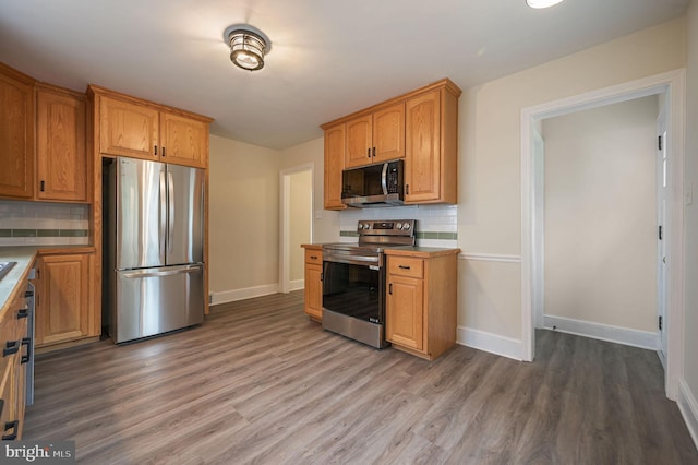 kitchen with light wood finished floors, tasteful backsplash, baseboards, brown cabinetry, and stainless steel appliances