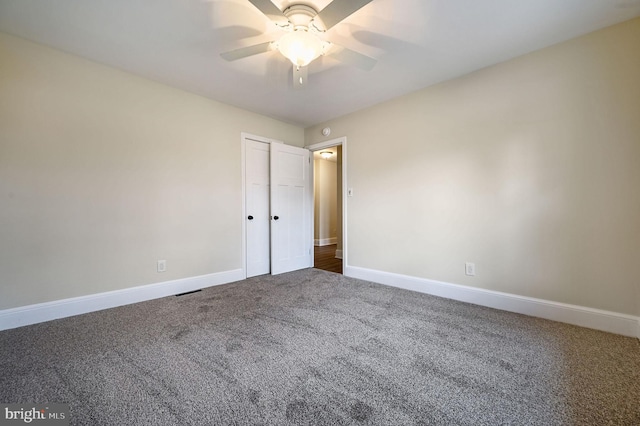 carpeted empty room with ceiling fan and baseboards