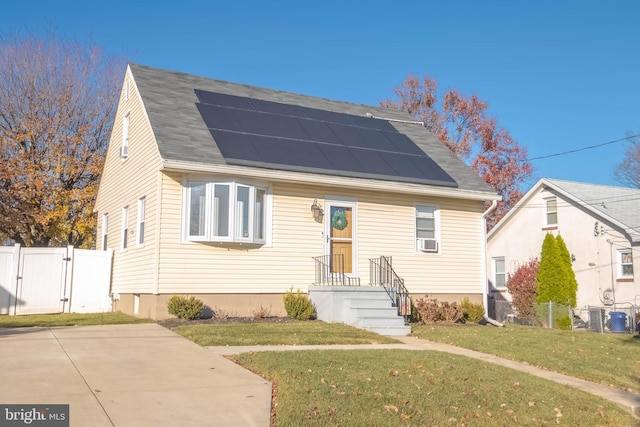 bungalow-style house with solar panels, a front yard, fence, and a gate