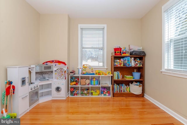 game room featuring light wood-type flooring, baseboards, and a wealth of natural light