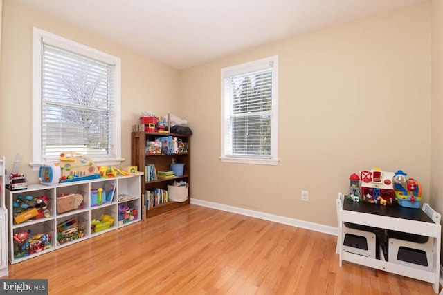 game room featuring light wood-style flooring, a wealth of natural light, and baseboards