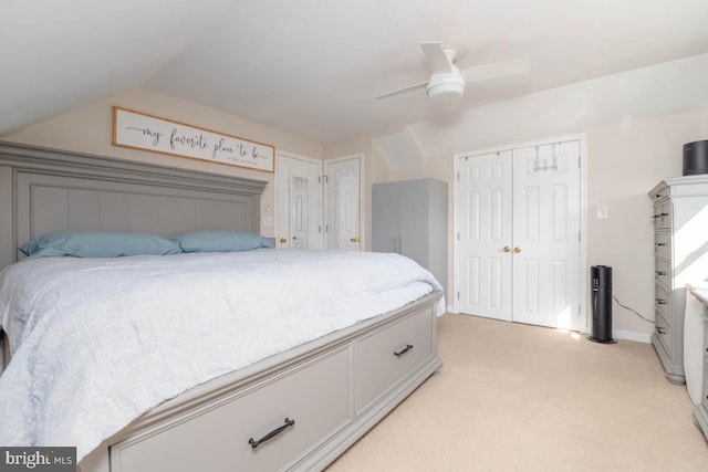 bedroom with lofted ceiling, multiple closets, a ceiling fan, and light colored carpet