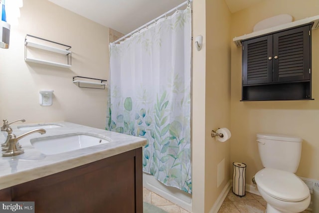 bathroom featuring double vanity, baseboards, toilet, tile patterned floors, and a sink