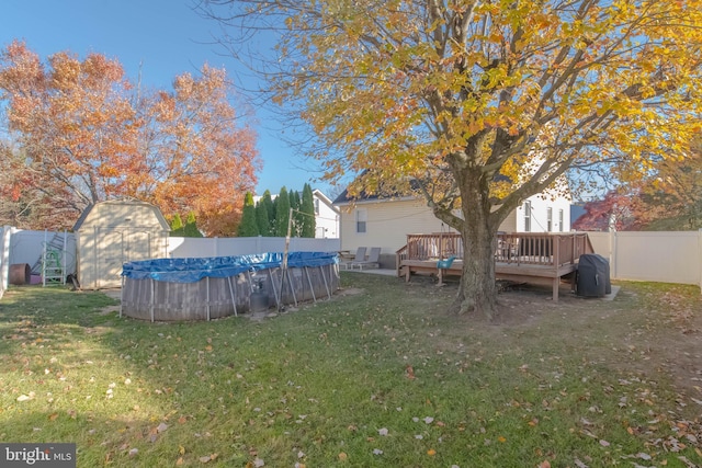 view of yard featuring a fenced in pool, a fenced backyard, an outbuilding, a storage unit, and a wooden deck