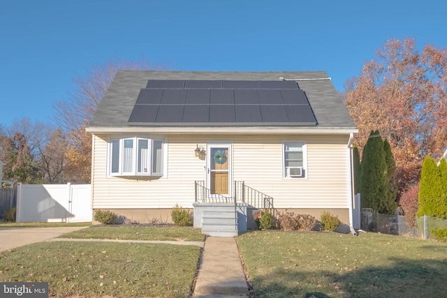 view of front of home with solar panels, a front yard, fence, and a gate