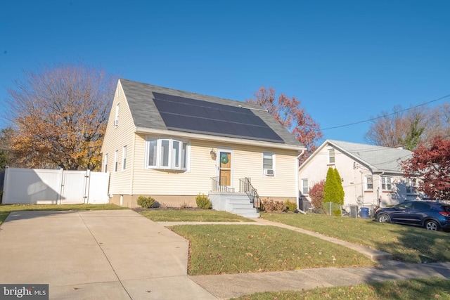 bungalow-style home featuring roof mounted solar panels, a gate, fence, and a front yard