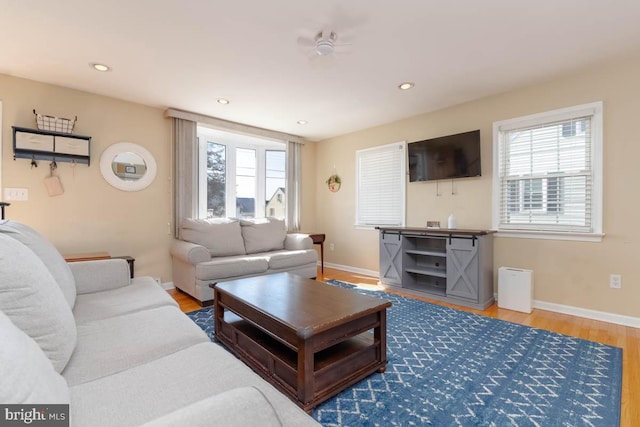 living room featuring recessed lighting, a healthy amount of sunlight, baseboards, and wood finished floors