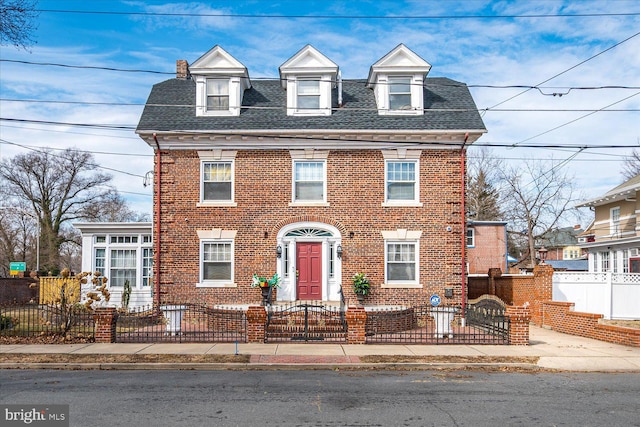 view of front of home with a fenced front yard, brick siding, and a shingled roof