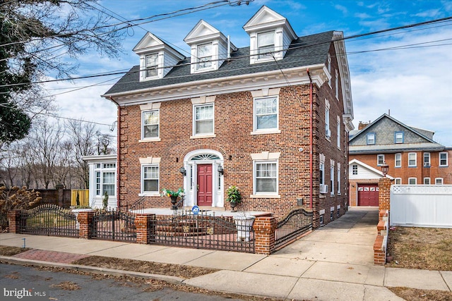 view of front of house featuring a shingled roof, a fenced front yard, a gate, an outdoor structure, and brick siding