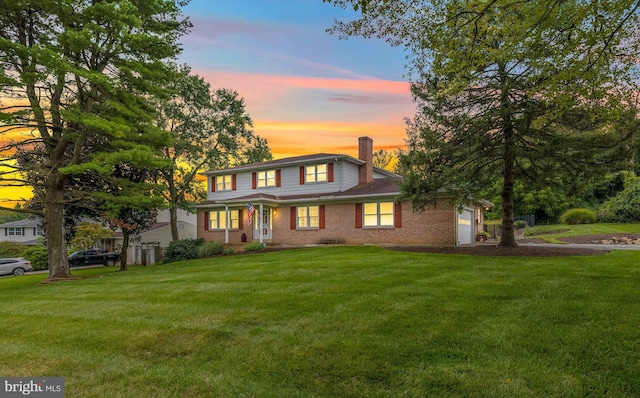 view of front of house featuring an attached garage, brick siding, a chimney, and a front yard