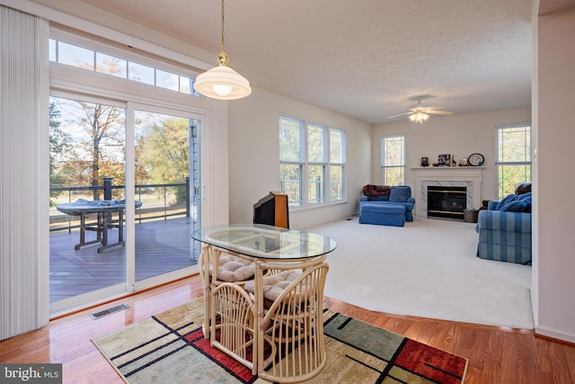 dining room featuring ceiling fan, a premium fireplace, visible vents, and wood finished floors