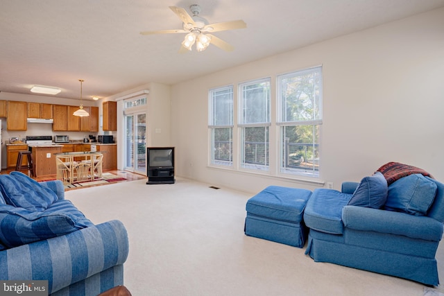 living room featuring a toaster, a ceiling fan, and light colored carpet