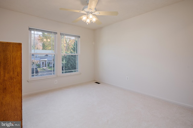 carpeted spare room with baseboards, visible vents, and a ceiling fan