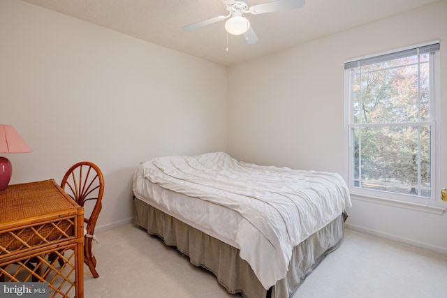 bedroom featuring light carpet, multiple windows, a ceiling fan, and baseboards