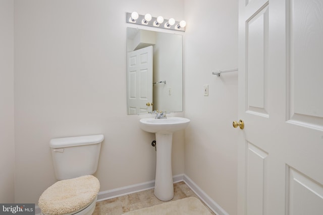 half bath featuring toilet and baseboards