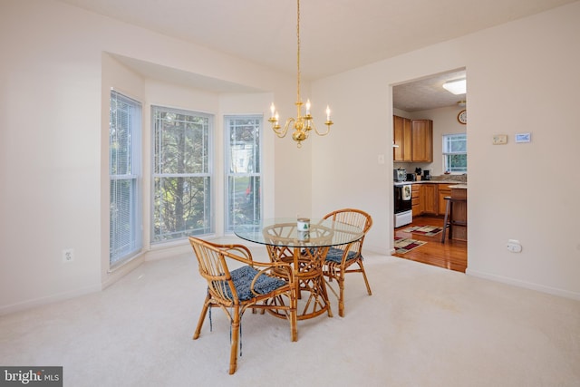 dining room with light carpet, an inviting chandelier, and baseboards