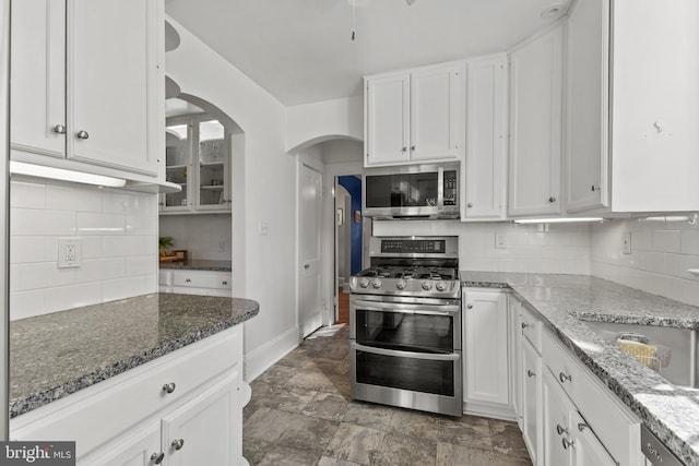 kitchen featuring stainless steel appliances, stone countertops, decorative backsplash, and white cabinets