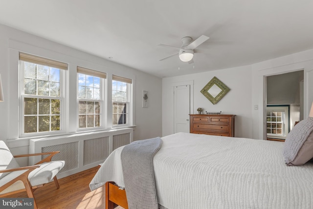 bedroom with light wood-type flooring, radiator heating unit, and ceiling fan