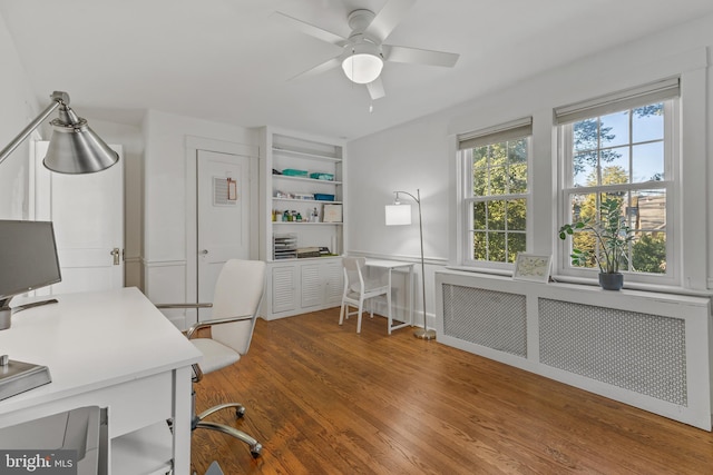 office with ceiling fan, wainscoting, wood finished floors, and radiator