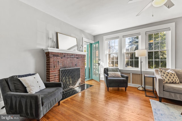 living area with a brick fireplace and wood-type flooring