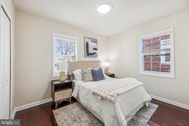 bedroom with a closet, dark wood finished floors, and baseboards