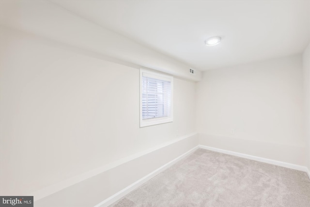 spare room featuring light carpet and baseboards