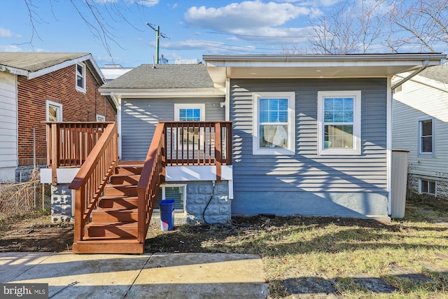 view of front of house featuring a shingled roof, stairs, and a wooden deck