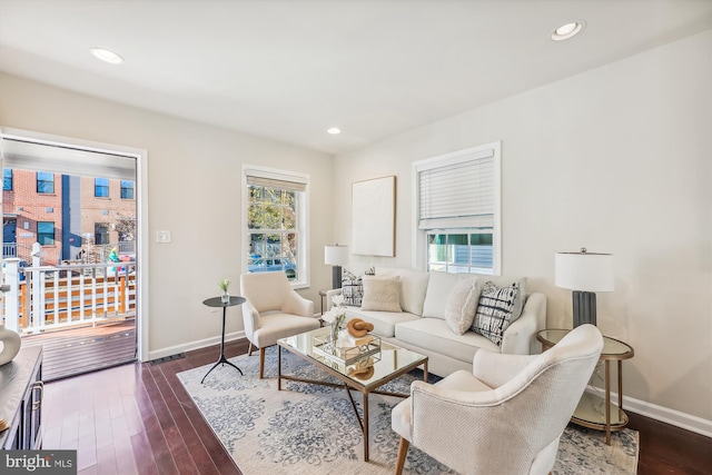 living room with dark wood-type flooring, plenty of natural light, and baseboards