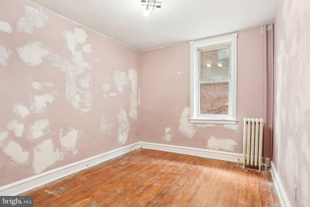 unfurnished room with radiator, wood-type flooring, and baseboards