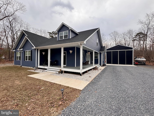 view of front of property with driveway, covered porch, a shingled roof, and an outbuilding