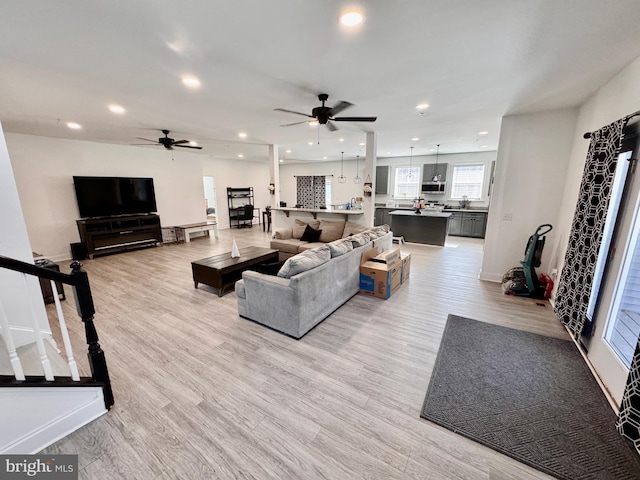 living area featuring a ceiling fan, recessed lighting, stairway, and light wood finished floors