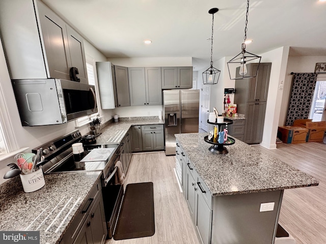 kitchen with light stone countertops, light wood-style flooring, stainless steel appliances, and a center island