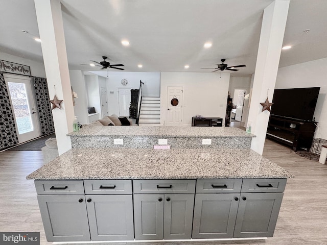 kitchen featuring light stone counters, recessed lighting, gray cabinetry, open floor plan, and light wood-type flooring