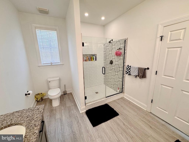 bathroom featuring visible vents, a shower stall, toilet, and wood finished floors