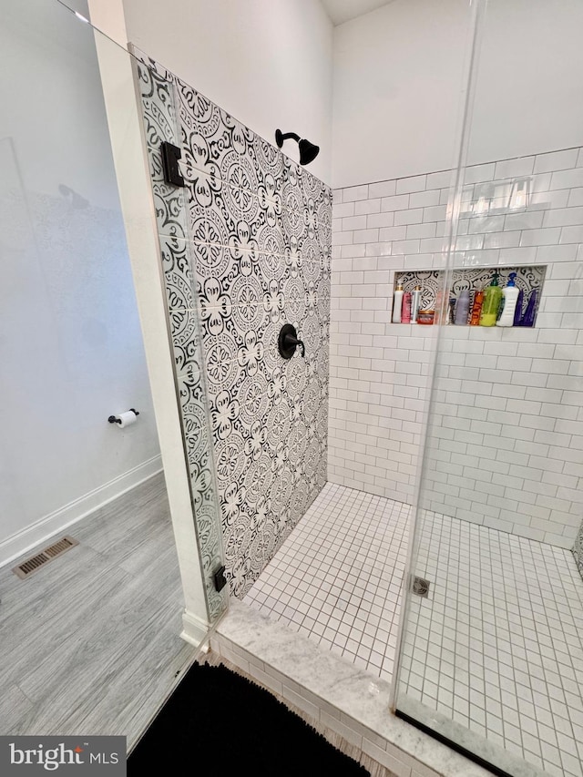 full bath featuring wood finished floors, a shower stall, visible vents, and baseboards