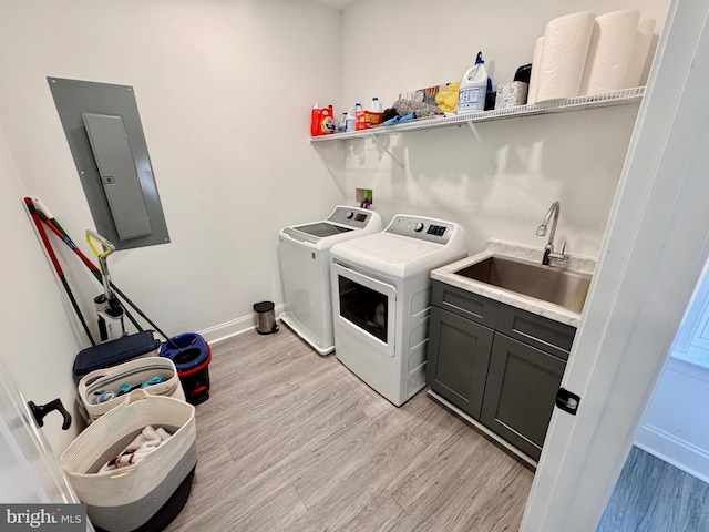 washroom featuring a sink, light wood-type flooring, independent washer and dryer, cabinet space, and electric panel