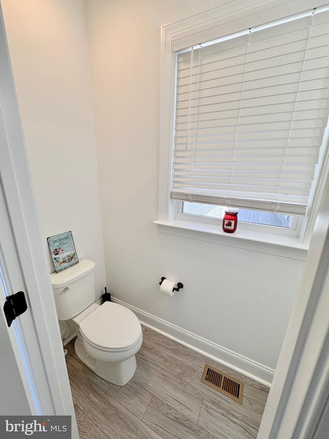 bathroom featuring baseboards, visible vents, toilet, and wood finished floors