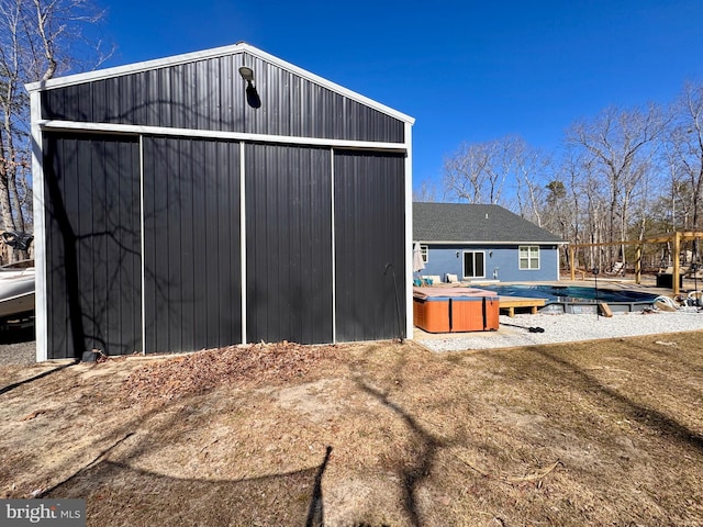 rear view of property with a garage, an outbuilding, a covered pool, and an outdoor structure