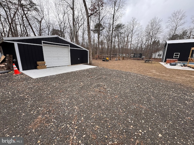 view of yard featuring a garage, an outbuilding, and dirt driveway