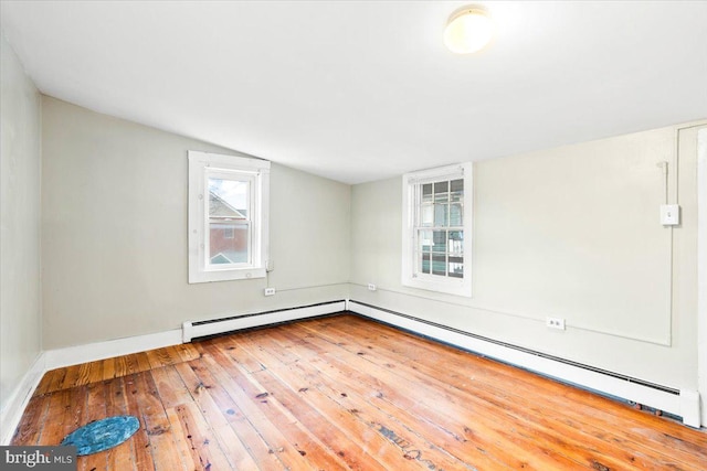 unfurnished room with a baseboard radiator, wood-type flooring, vaulted ceiling, and baseboards