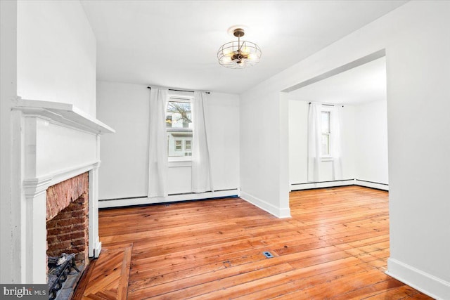 unfurnished living room featuring baseboards, a baseboard radiator, hardwood / wood-style floors, a fireplace, and a baseboard heating unit