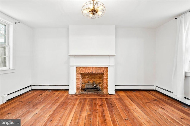 unfurnished living room featuring a chandelier, hardwood / wood-style floors, baseboard heating, and a brick fireplace