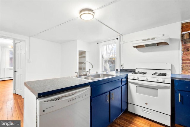 kitchen featuring white appliances, wood-type flooring, blue cabinets, under cabinet range hood, and a sink