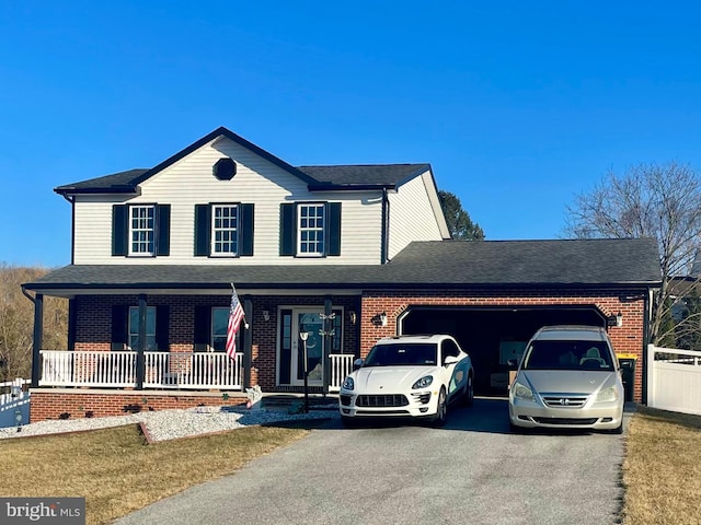 view of front facade featuring roof with shingles, an attached garage, covered porch, aphalt driveway, and brick siding