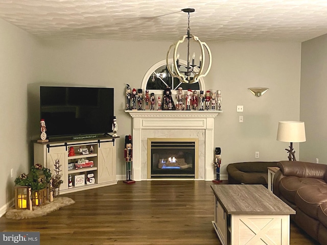 living area with a high end fireplace, a textured ceiling, an inviting chandelier, and dark wood-style flooring