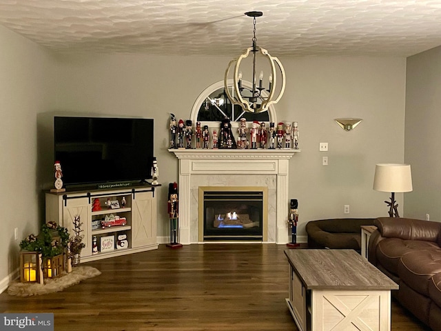 living area with dark wood-type flooring, a notable chandelier, a fireplace, and a textured ceiling