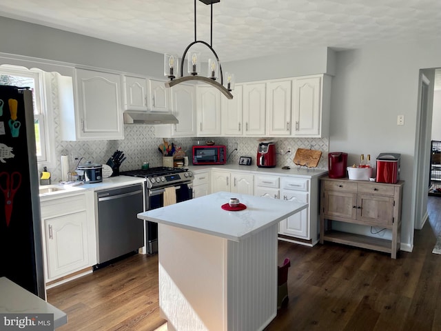 kitchen with under cabinet range hood, dark wood finished floors, light countertops, appliances with stainless steel finishes, and white cabinets