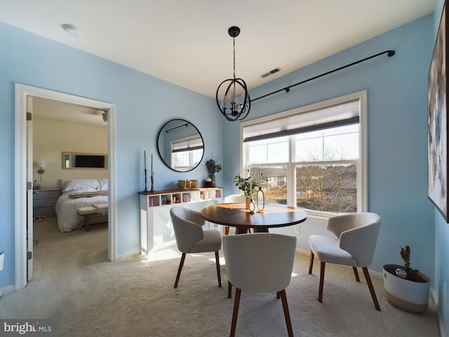 carpeted dining room with visible vents, a chandelier, and baseboards