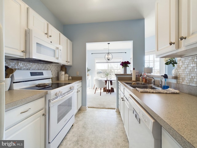 kitchen with white appliances, a sink, white cabinetry, light countertops, and tasteful backsplash